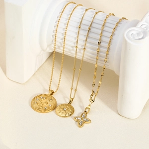 Detailed view of triple layered gold necklaces with snake and star charms on white pillars