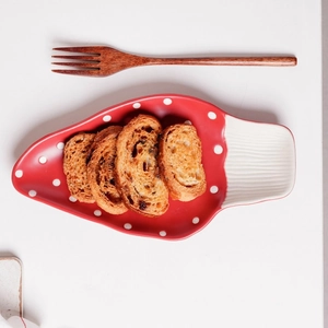 Top-down view of a red ceramic strawberry plate with white polka dots holding toast slices