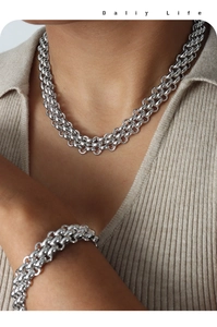 Detail of silver heavy chunky link chain necklace and bracelet set on ribbed sweater