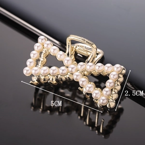 Macro detail of a pearl bow hair claw clip on mirror surface with 5cm size dimensions