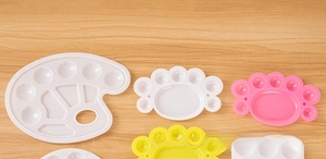 Close-up of colorful plastic paint palettes in foot and flower shapes for art students