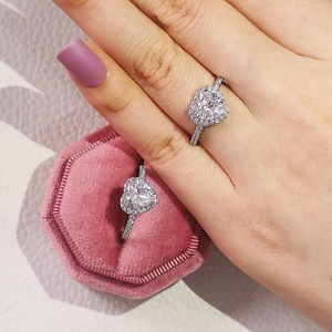 Detail of a sparkling silver heart-shaped halo diamond ring in a velvet jewelry box