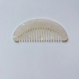 Detail of cream marble acetate hair comb with pearlescent finish and wide teeth