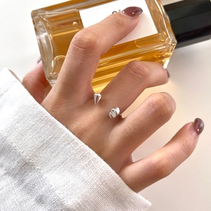 Detail of minimalist S925 sterling silver open ring on model's hand holding perfume