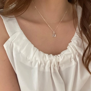 Detail of a minimalist 925 silver necklace with a square turquoise pendant on a model