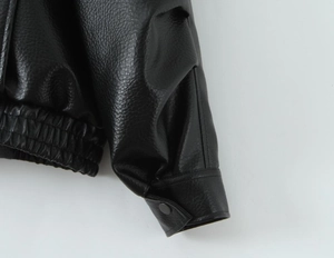 Details von Ledertextur, elastischem Saum und Bündchen an der schwarzen Bikerjacke