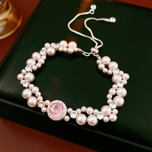 Close-up of pearl bracelet with pink gemstone on green leather background