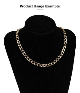 Close-up of golden flat Cuban chain necklace displayed on a black velvet bust stand