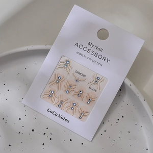 Detail of dark blue rhinestone and gold wave line nail stickers in branded packaging
