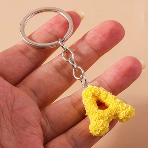 Macro shot of letter A keychain with yellow rose floral details and silver ring