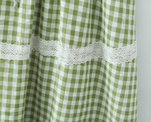 Close-up of green and white gingham fabric with exquisite white lace trim and stitching