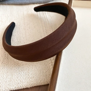 Makro-Detail eines braunen Stoffstirnbands mit vertikaler Textur und breitem Design