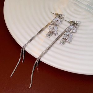 Detailed close-up of silver tassel earrings with leaf-shaped cubic zirconia on ceramic