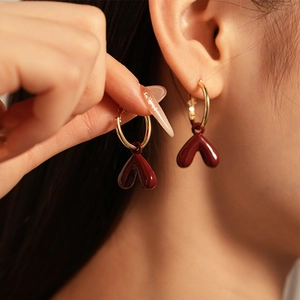 Close-up of heart-shaped burgundy red earrings with gold plated hoops for women