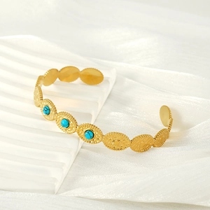 Detail of a gold-plated stainless steel open cuff bangle with oval turquoise inlay