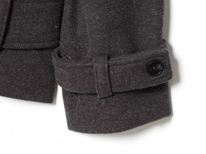 Detail of dark grey wool coat sleeve featuring black buttons and adjustable cuff straps