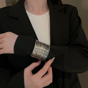 Detail of layered silver wire wrap cuff bracelet on model wearing black blazer