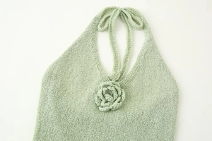 Detail of light green knit halter top featuring a 3D knitted flower decoration
