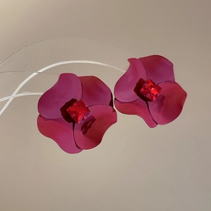 Macro detail of red floral earrings with matte petals and centered square rhinestone