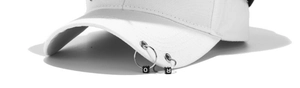 Detail of white baseball cap brim featuring two silver metal rings and letter beads