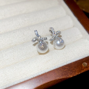 Detail van zilveren strikoorbellen met zirkonia en witte ronde parelhangers