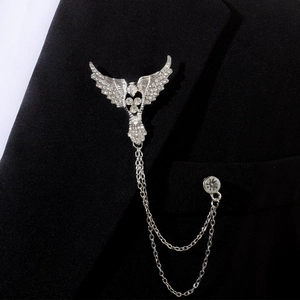 Détail d'une broche aigle argentée avec strass et chaîne à pampilles sur revers noir