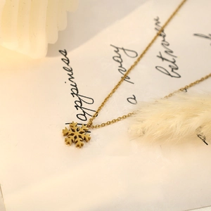 Close-up of a stylish 18k gold-plated snowflake pendant on a delicate cable chain