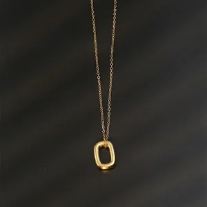 Close-up of polished gold oval pendant on a delicate chain over black texture background