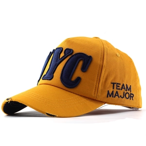 Detail of yellow baseball cap with NYC embroidery and distressed brim texture