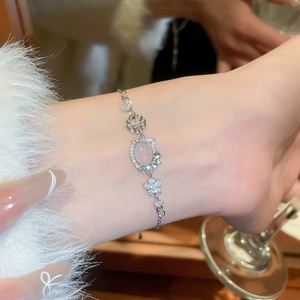 Close-up of silver bracelet with pink kitten opal pendant and diamond flower charms