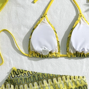 Gros plan sur la texture brodée ondulée du haut de bikini jaune avec étiquette de soin