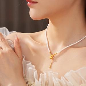 Detail view of pearl necklace with golden gourd and tassel pendant on female neck
