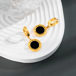 Detailed macro shot of gold hollow Roman numeral earrings with black round pendants