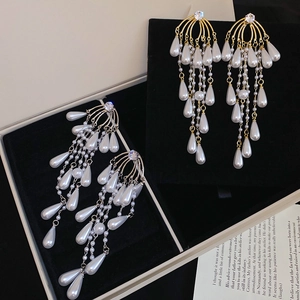 Macro shot of long tassel pearl earrings with sparkling rhinestones in gold and silver