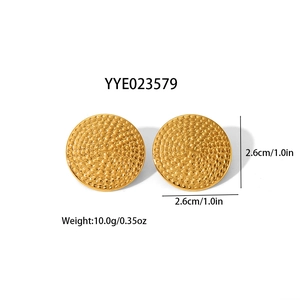 Détail des boucles d'oreilles dorées de 2,6 cm avec une texture tissée en relief