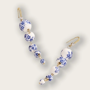 Detail showing gradient porcelain beads with blue floral patterns and gold hooks