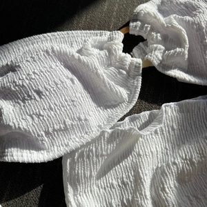 Detail of white textured bikini top with bubble crepe fabric and brown decorative ring