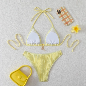 Detailed flat lay of yellow textured bikini with gold star charms on white faux fur background
