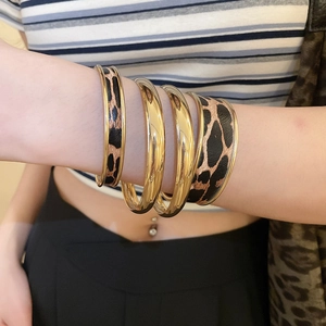 Close-up of four-piece gold bracelet set with leopard print patterns and layered style