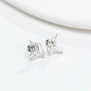 Detailed close-up of hollow silver swallow bird stud earrings with a polished metallic finish