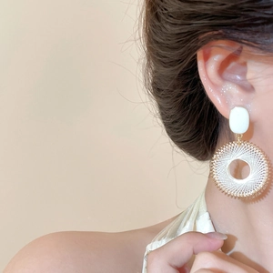 Gros plan de boucles d'oreilles créoles bohèmes tissées portées par un mannequin