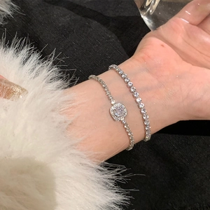 Détail du bracelet tennis argenté et de la chaîne à pendentif carré avec zircons