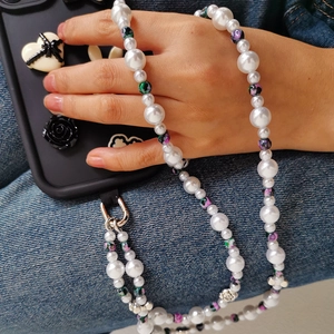 Detail of beaded pearl phone strap with floral charms and silver metal clasp on phone case