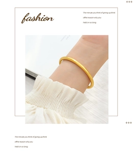 Close-up of minimalist matte gold finish round bangle worn on wrist with soft lighting