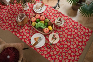 Close-up of red Christmas tablecloth with gingerbread man and festive tree patterns