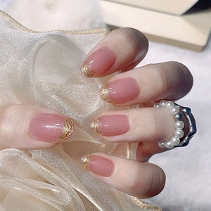 Handmade pink press-on nails with 3D gold embossed lines in a short round French style