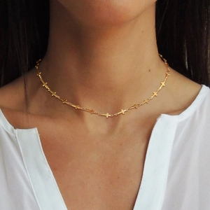 Minimalist gold stainless steel necklace featuring a linked cross design on model
