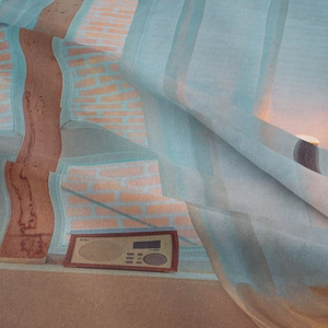 Detailed macro view of bohemian tapestry fabric showing soft folds and vintage radio print