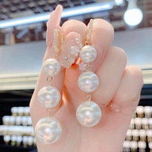 Close-up of triple-layered baroque pearl drop earrings with elegant gold setting