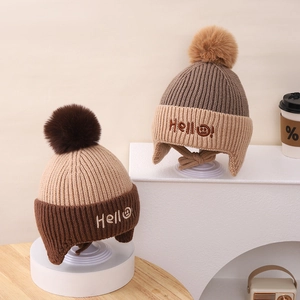Detailed view of kids winter knit earflap hats with Hello embroidery and fluffy pom-poms